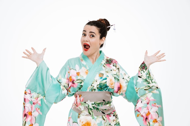 Donna in kimono giapponese tradizionale felice e sorpresa che alza le braccia su bianco