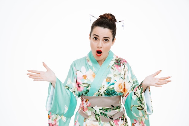 Woman in traditional japanese kimono surprised and confused spreading arms to the sides on white