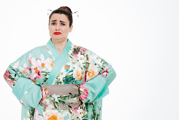 Woman in traditional japanese kimono with sad expression pursing lips on white