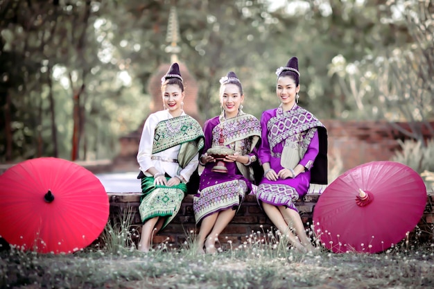 A woman in traditional Lao costumes sitting while making merit at the temple during Songkran Festival and Thai and Lao New Year