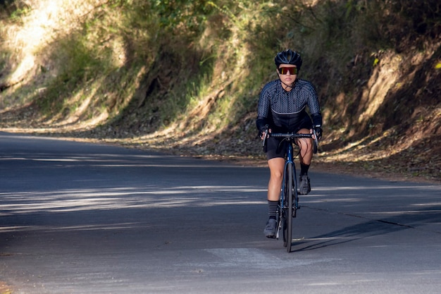 Женщина на велосипеде по тропе на дороге посреди концепции спорта на открытом воздухе в лесу