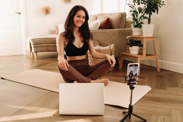写真 女性の自宅でのオンライントレーニング フィットネスブロガーがスマートフォンでトレーニングのビデオを録音