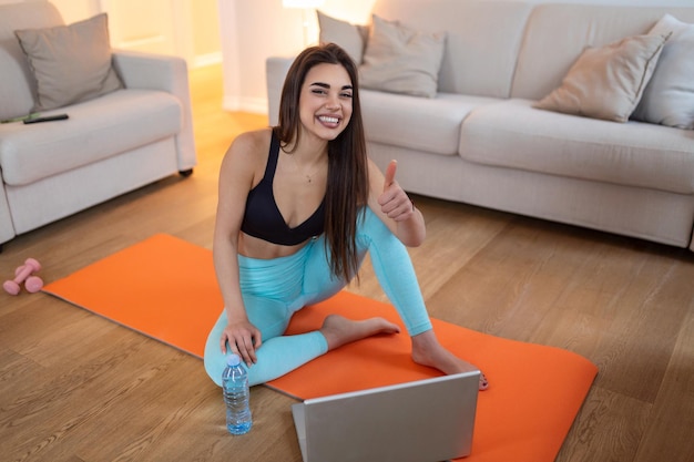 Woman training at home doing workout and watching videos on laptop Beautiful woman is doing exercise She is watching video on the internet and repeating the tasks