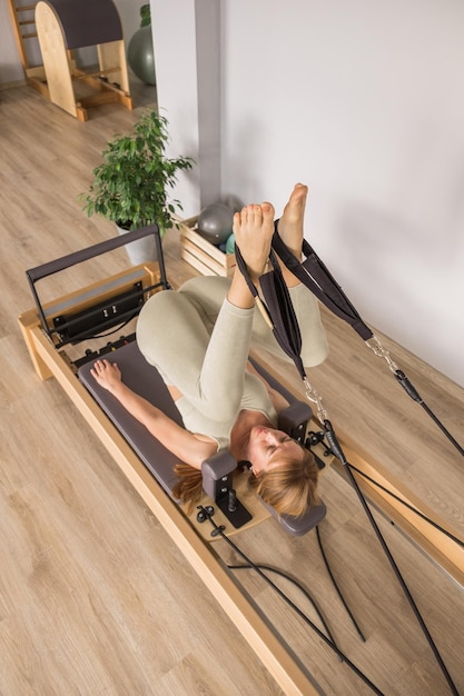 Foto donna che allena pilates sul letto del riformatore macchina da studio per pilates del riformatore per allenamenti fitness in g