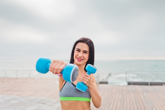 Woman training with dumbbells on the beach