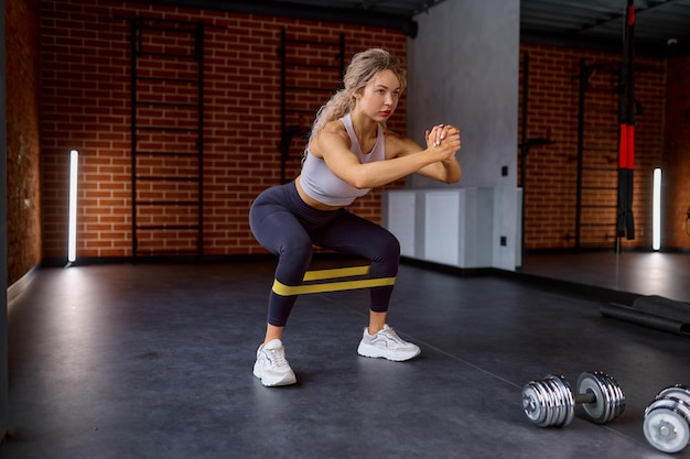 Allenamento donna con elastico fitness in palestra sport club. esercizio di allenamento per gambe e pompa del bottino