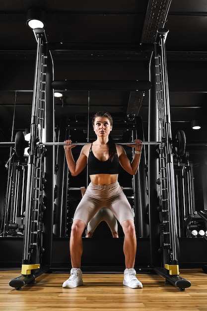 Woman trains legs doing exercises with heavy weight