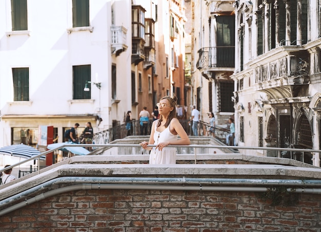女性旅行イタリア女の子はヴェネツィアの景色を楽しむヴェネツィアの街を歩く女性観光客