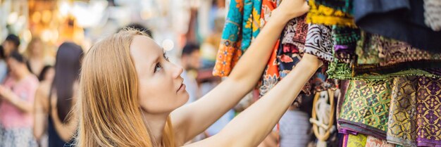 Woman traveler choose souvenirs in the market at ubud in bali indonesia banner long format