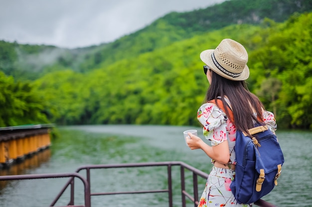 コーヒーを飲み、川と山の景色を探している女性旅行者。