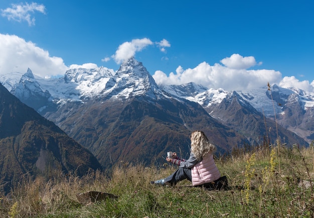 여성 여행자는 산 풍경을 볼 수있는 커피를 마신다
