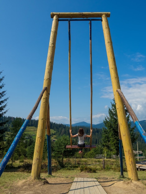 Woman traveler enjoying of swinging on heavenly swing and mountain view