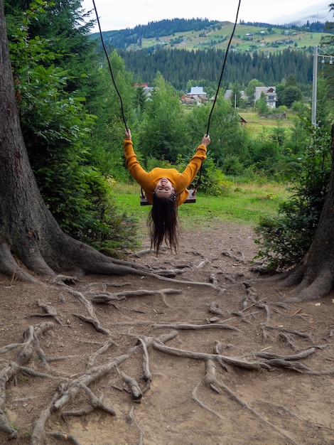 Woman traveler enjoying of swinging on swing and mountain view