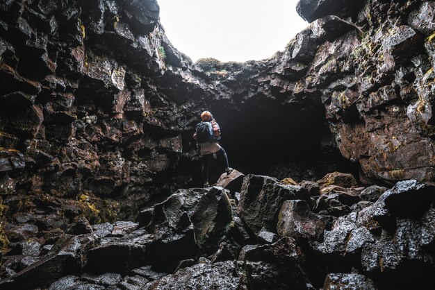女性旅行者はアイスランドの溶岩トンネルを探索します。