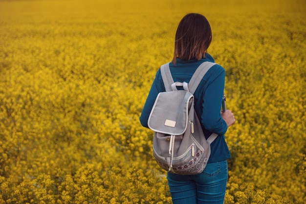 Woman traveler in a flowering rapeseed field
