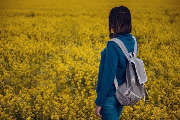 Woman traveler in a flowering rapeseed field