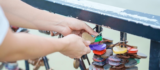 Woman Traveler hand lock key during travel in Da Nang Tourist sightseeing at love lock bridge Landmark and popular Vietnam and Southeast Asia travel concept