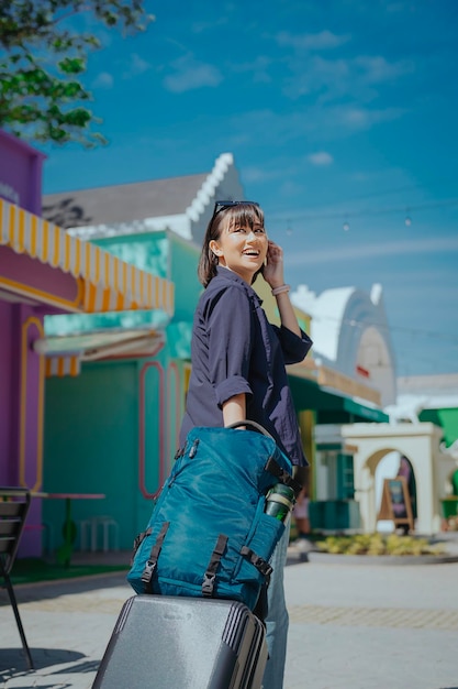 a woman traveler is walking and pushing her suitcase and backpack