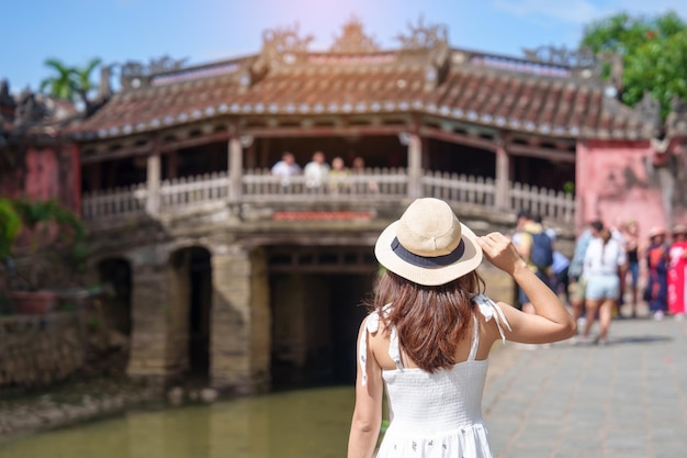 Photo woman traveler sightseeing at japanese covered bridge or cau temple in hoi an ancient town vietnam landmark and popular for tourist attractions vietnam and southeast asia travel concept