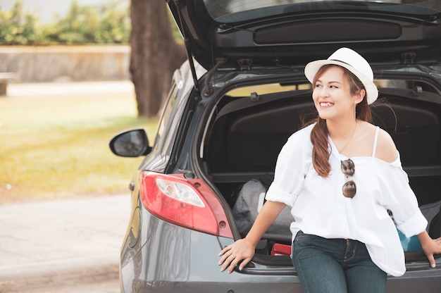 Woman traveler sitting on hatchback car