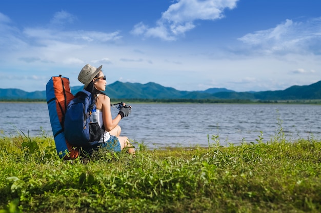 写真 山の湖のそばに座っている女性旅行者