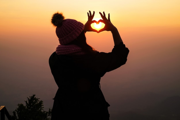 写真 山の上に立っていると日没時に自然の景色を楽しんでいる女性旅行者。