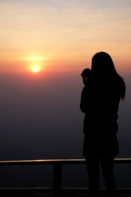 写真 山の上に立って、休日に自然の写真を撮る女性旅行者。