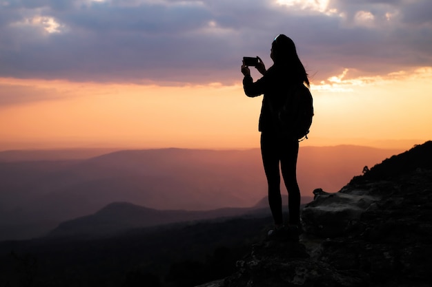 写真 山の上に立って、休日に自然の写真を撮る女性旅行者。