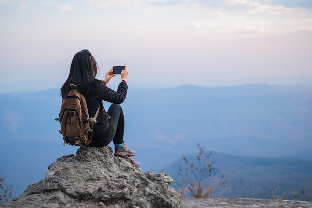 写真 山の上に立って、休日に自然の写真を撮る女性旅行者。