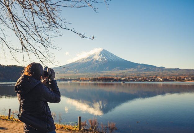 Женщина-путешественница фотографирует гору Фудзи сан на озере Кавагутико