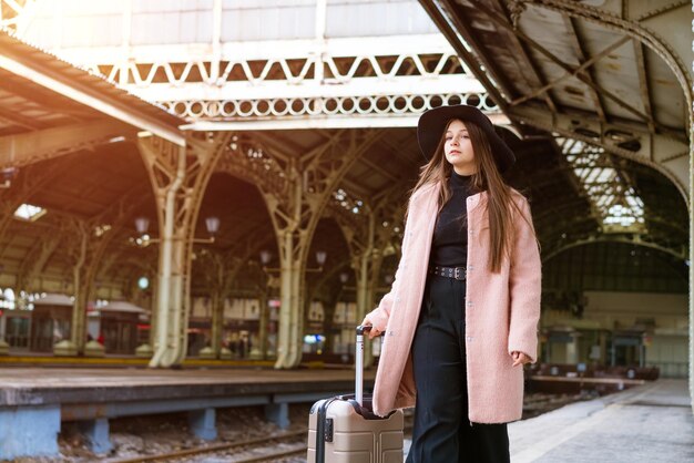 Женщина-путешественница-турист гуляет с багажом на вокзале. Концепция активного и путешествующего образа жизни в ...