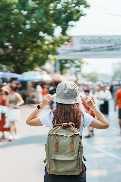 Woman traveler visiting in Bangkok Tourist with backpack and hat sightseeing in Chatuchak Weekend Market landmark and popular attractions in Bangkok Thailand Travel in Southeast Asia concept