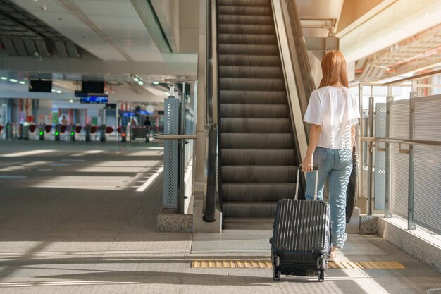 Фото Женщина-путешественница, идущая по международному аэропорту или платформе метро