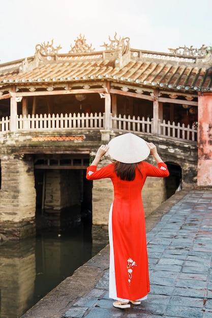 베트남 호이안(Hoi An) 마을의 일본 덮힌 다리에서 아오자이(Ao Dai) 베트남 옷을 입은 여성 여행자