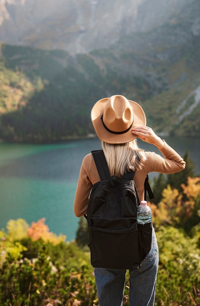 帽子をかぶって、素晴らしい山や湖、放浪癖の旅行の概念を見ている女性旅行者。ポーランドのタトラ山脈にあるモルスコイ湖の目。