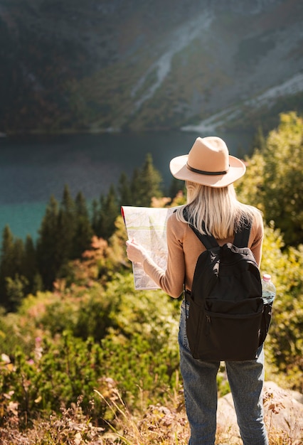 帽子をかぶって、素晴らしい山や湖、放浪癖の旅行の概念を見ている女性旅行者。ポーランドのタトラ山脈にあるモルスコイ湖の目。