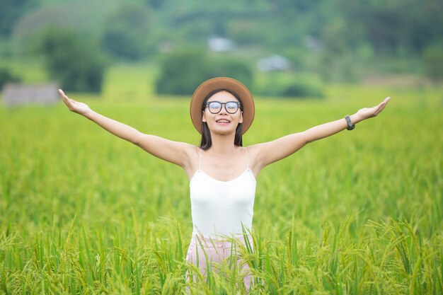 Il viaggiatore della donna con il cappello dello zaino e l'esame si trova su un prato nelle montagne.