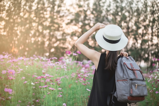 женщина путешественник с рюкзаком и глядя на удивительные красивые цветочные поля
