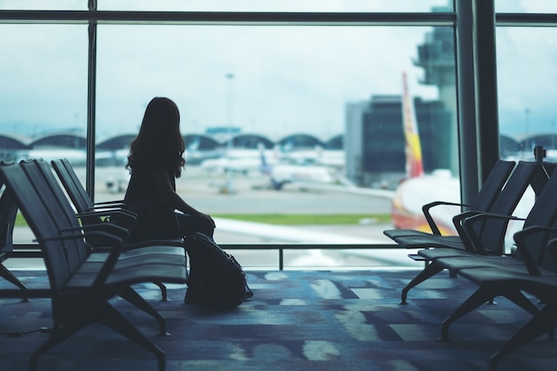 A woman traveler with backpack sitting and waiting at the airport