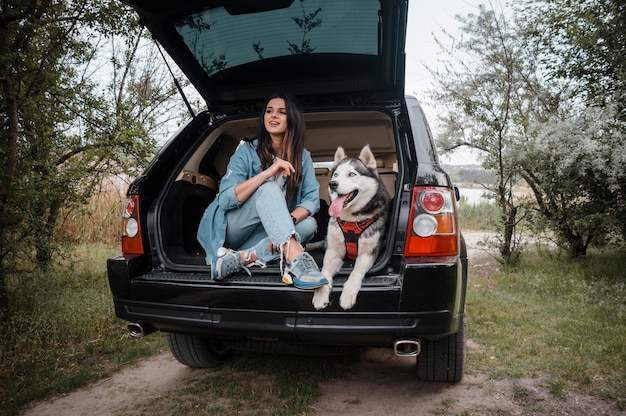 Foto donna che viaggia in macchina con il suo husky