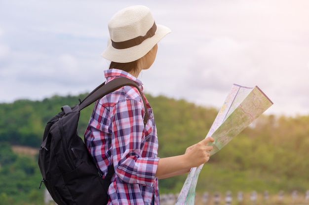 旅行地図を持って山を見て女性