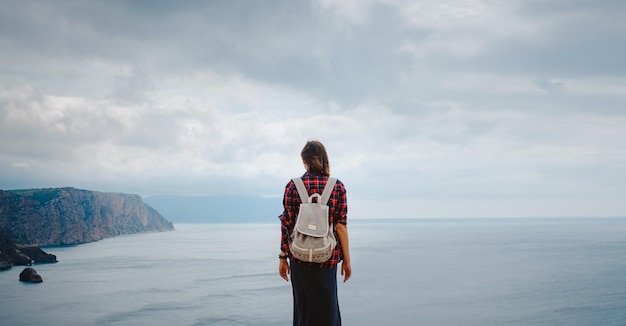 Woman traveling with backpack tourist on seashore in summer