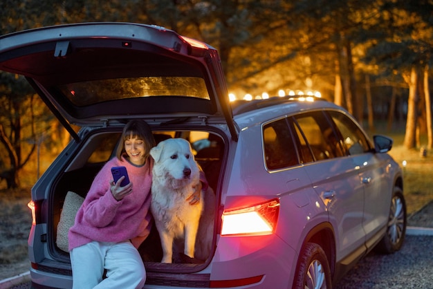 自然の上を車で犬と一緒に旅行する女性