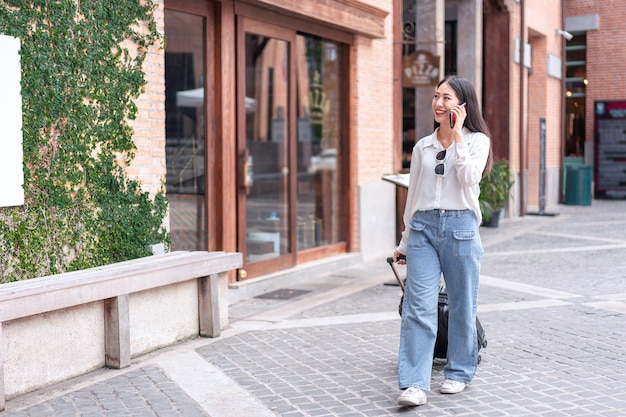 woman traveller using smartphone and dragging black suitcase