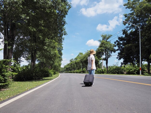 通りに沿って荷物を片手に歩いている女性旅行者