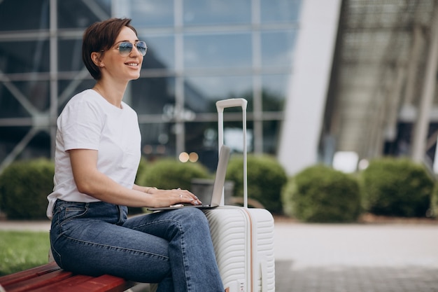 空港で旅行し、コンピューターで作業している女性