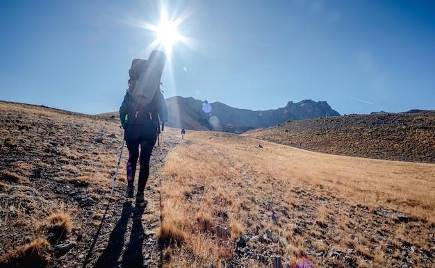 明るい太陽の下でパノラマのトルコの山々をトレッキングする女性