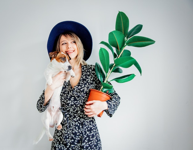 Donna in abito alla moda con la pianta in una pentola e cane