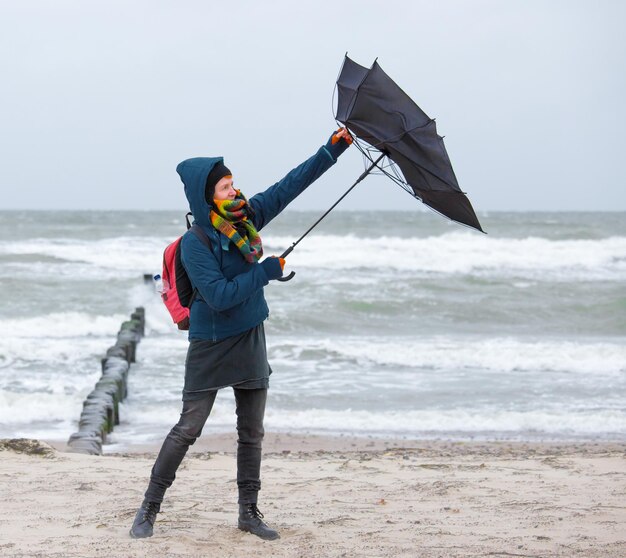 Photo a woman tries to open an umbrella in stormy weather