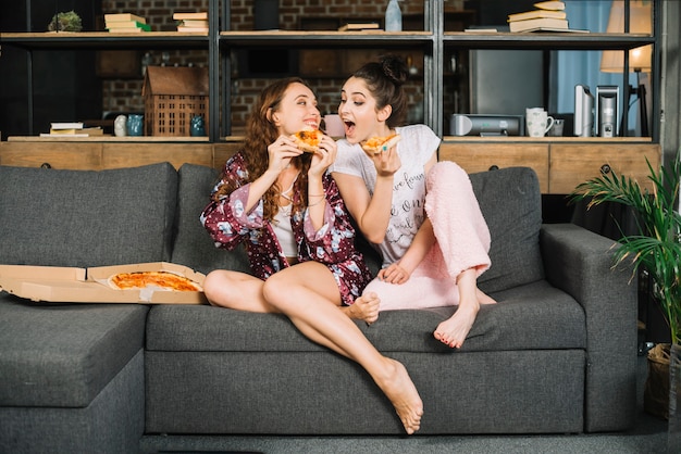 Foto donna che prova a mangiare la pizza della sua amica a casa